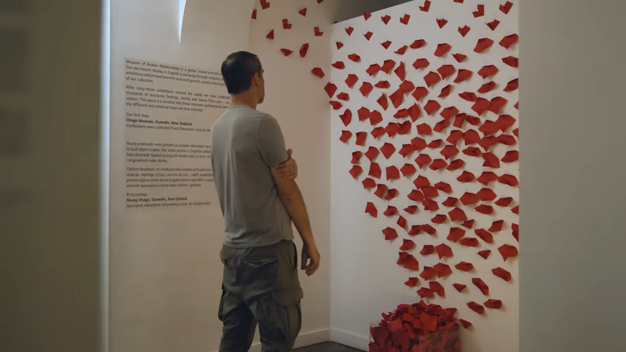 A man observes a wall decorated with red heart-shaped notes at the Museum of Broken Relationships in Zagreb