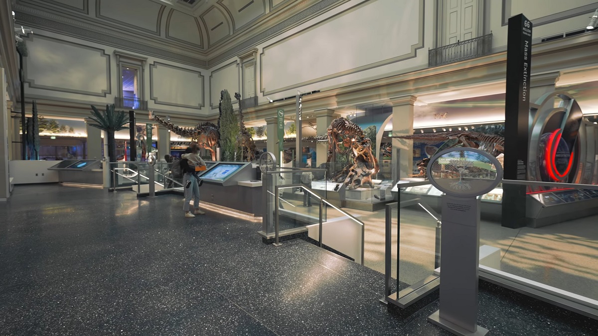 A spacious dinosaur exhibit hall filled with interactive displays, fossil skeletons, and educational panels