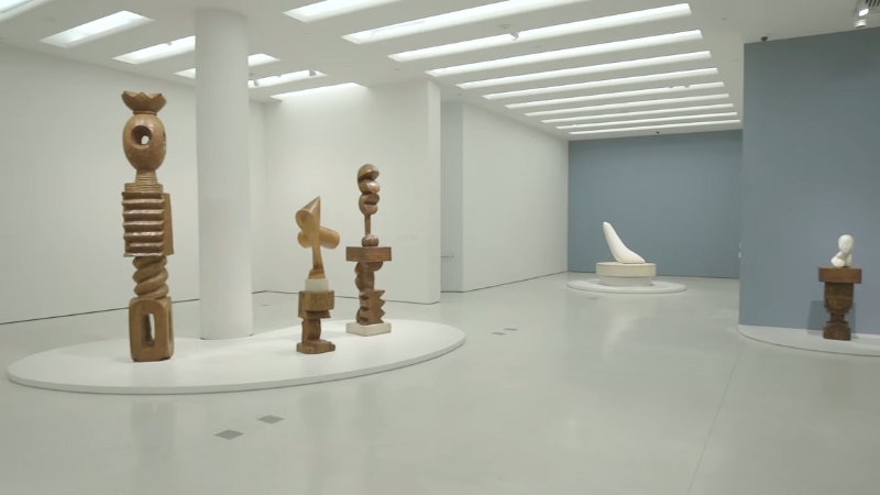 Wooden and stone sculptures are displayed in a bright, minimalist gallery at the Guggenheim Museum